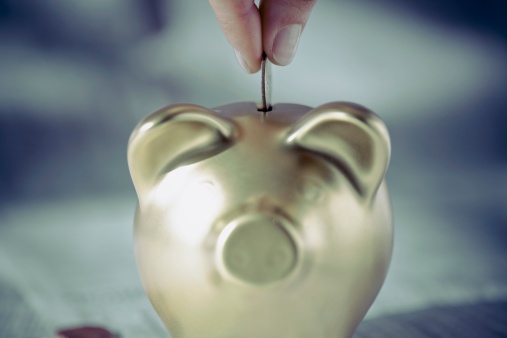 126530543_Persons_hand_putting_coin_into_a_piggy_bank.jpg